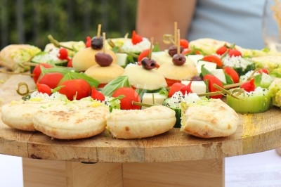 Traiteur Traiteur D'azur Saint-Vallier-de-Thiey #1 Plateau en bois garni de mini-pizzas, légumes frais et amuse-bouches, présenté sur une table en extérieur.