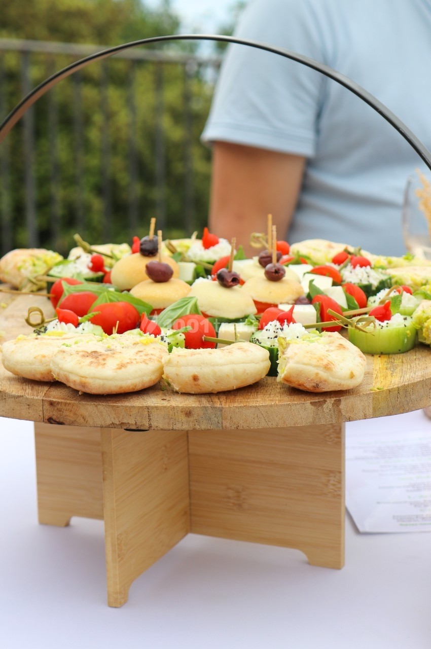 Traiteur Traiteur D'azur Saint-Vallier-de-Thiey #1 Plateau en bois garni de mini-pizzas, légumes frais et amuse-bouches, présenté sur une table en extérieur.