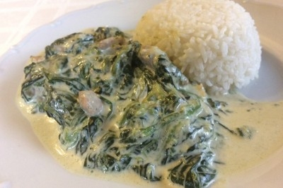 Poulet fafa Plat composé d'épinards à la crème accompagnés d'une portion de riz blanc sur une assiette blanche.