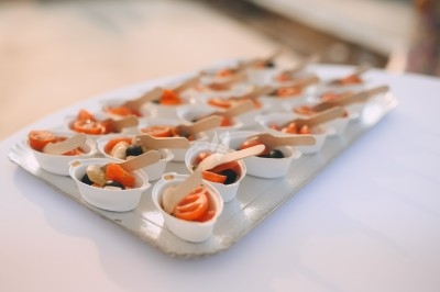 Plateau de verrines individuelles contenant des tranches de saumon, olives et petites cuillères en bois.