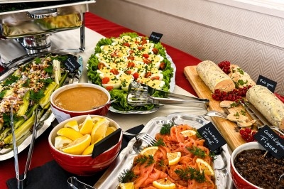 Buffet avec saumon fumé, foie gras, légumes, salade composée et condiments, présenté sur une table dressée.