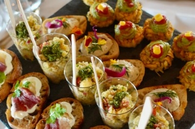 Plateau de bouchées apéritives variées, incluant toasts, verrines et amuse-bouches colorés, présenté sur une ardoise.