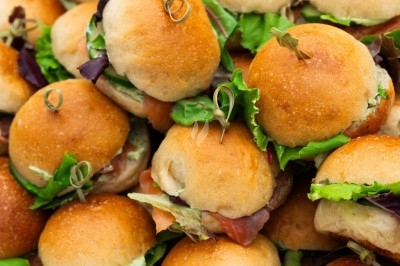 Traiteur Montagu Troyes #1 Plateau de mini-burgers garnis de salade et de charcuterie, présentés sur un support en bois.