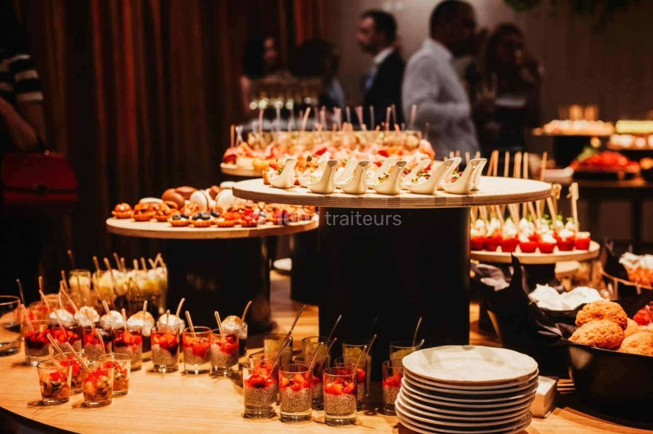 Buffet élégant avec une variété de verrines, amuse-bouches et desserts disposés sur des plateaux en bois.