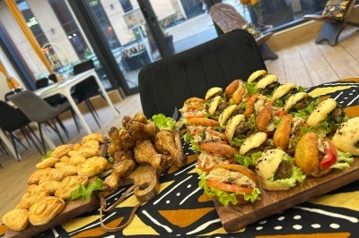 Traiteur Sora la Belle Chambly #2 Plateaux de mini-sandwichs variés, feuilletés et pilons de poulet disposés sur une table dans un restaurant lumineux.