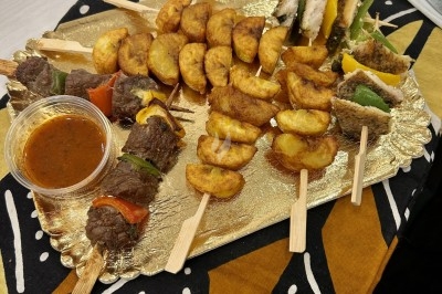 Plateau Brochetti (brochettes d'alloco, de poisson, de bœuf, de poulet) Plateau doré avec brochettes de viande, légumes, morceaux de poulet et plantains frits, accompagné d'une sauce.