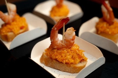 Crevettes sur des tranches de pain garnies d'une préparation orange, présentées dans des coupelles individuelles.