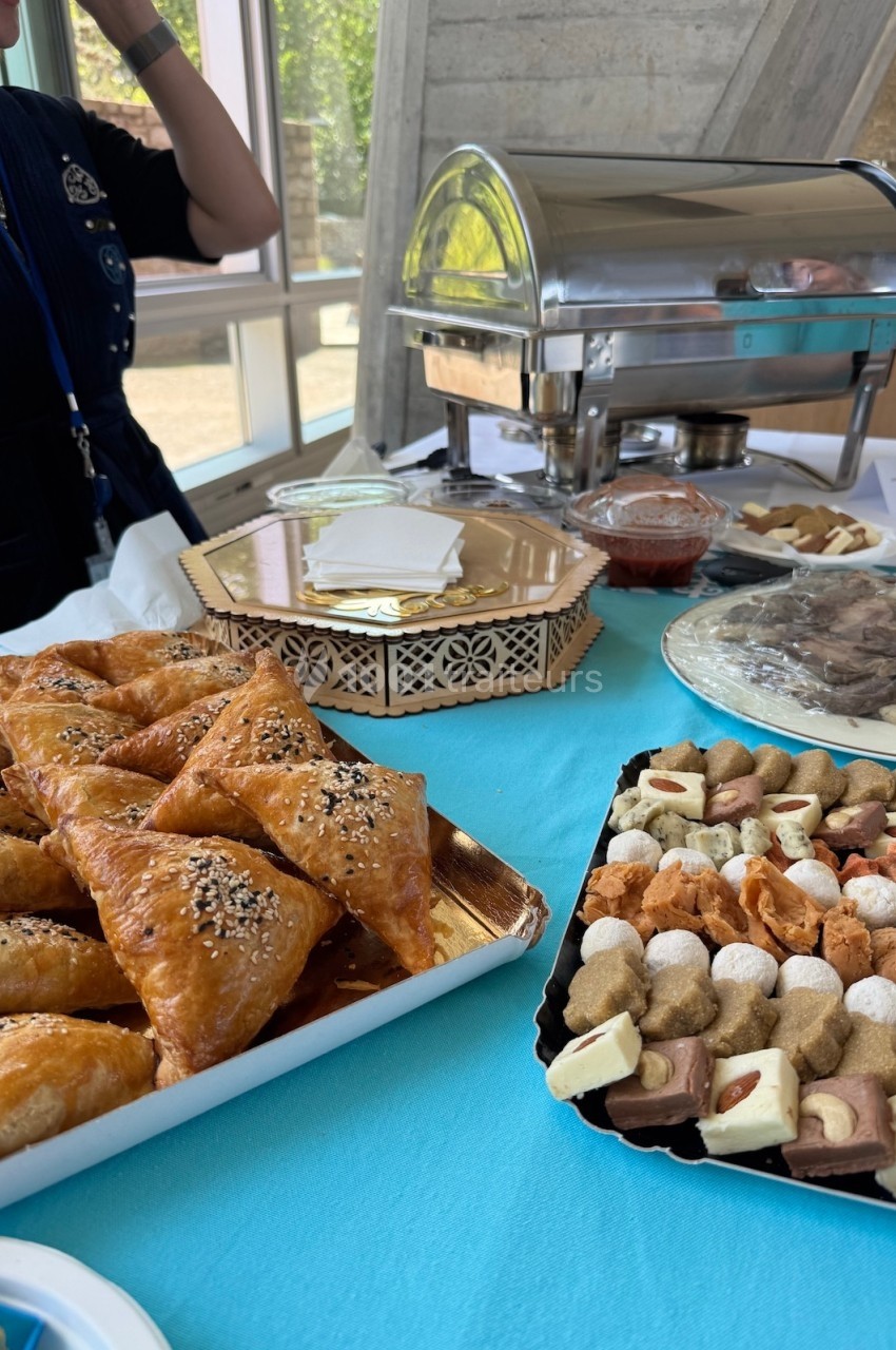 Assortiment de pâtisseries et de plats salés présentés sur une table avec un chafing dish en arrière-plan.