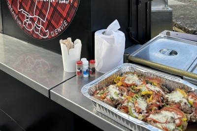 Traiteur Mémé Patate Kervignac #3 Plateau en aluminium contenant un plat cuisiné avec légumes, viande et fromage, posé sur un comptoir de food truck.