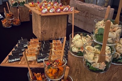 Buffet de verrines et amuse-bouches variés disposés sur des présentoirs en bois dans une salle élégante.