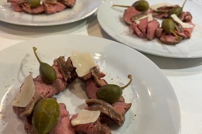 Traiteur La Cuisine By Alexandre Fréjus #5 Assiettes de carpaccio de bœuf garnies de câpres, anchois et copeaux de parmesan, disposées sur une table.