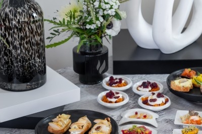 Assortiment de bouchées et amuse-bouches variés présentés sur une table avec des décorations modernes et florales.