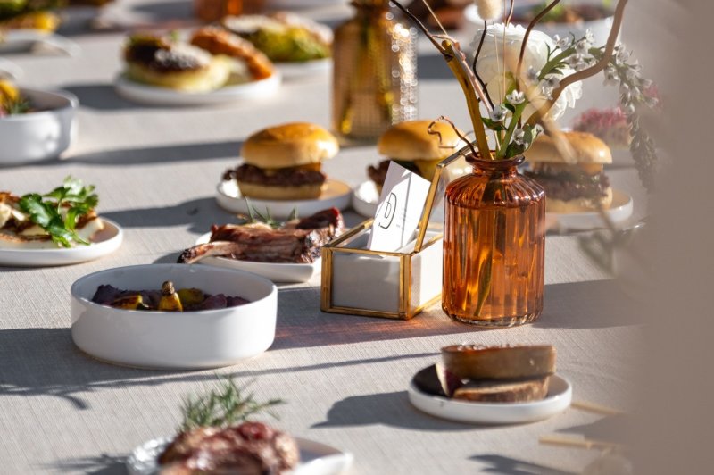 Table dressée avec divers plats, desserts et décorations florales dans des tons naturels et lumineux.
