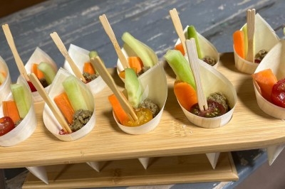 Coupelles en bois contenant des bâtonnets de légumes frais et sauce, présentées sur un support en bois.