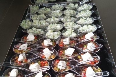 Cuillères apéritives alignées avec des préparations variées, incluant légumes, fromage frais et condiments.