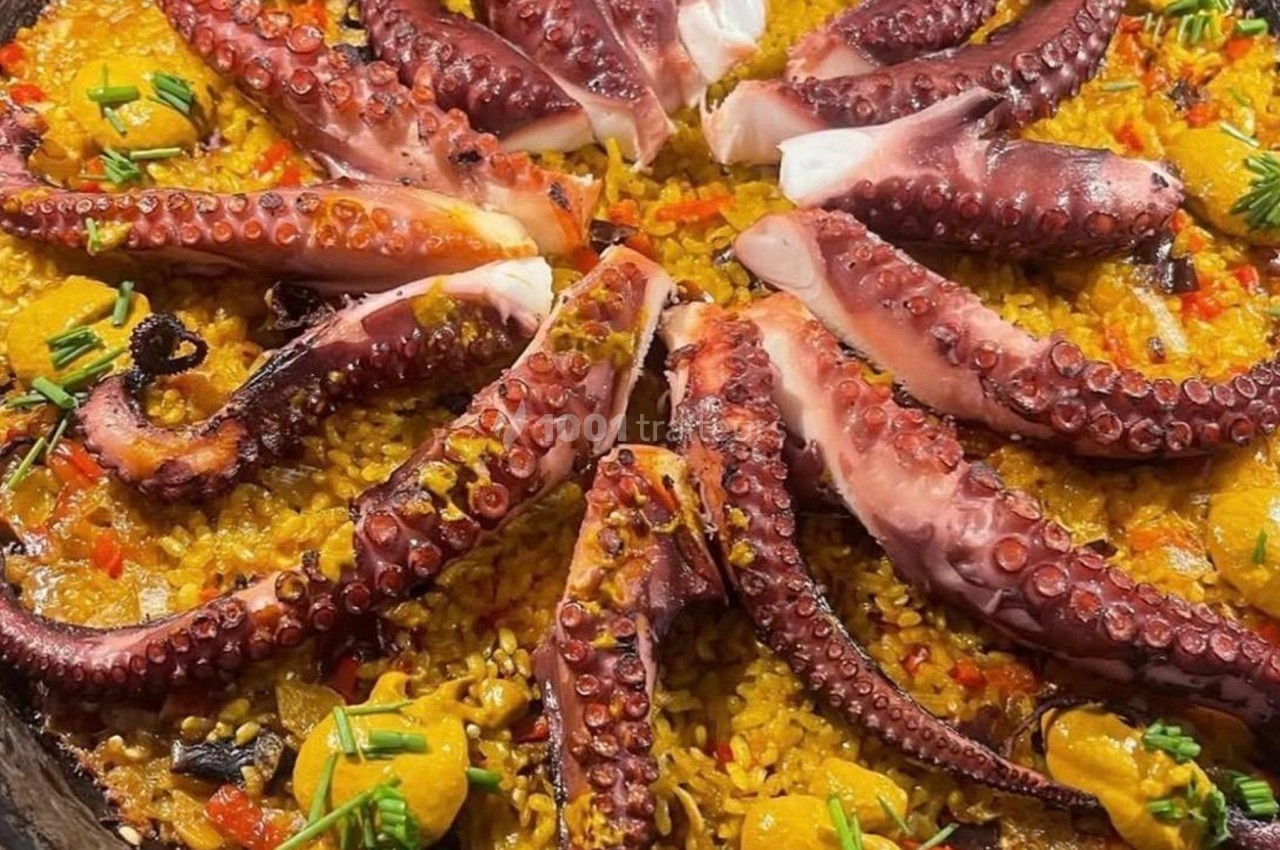 Plat de riz safrané garni de tentacules de poulpe grillées, de légumes et de touches de sauce jaune.