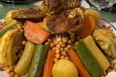 Plat de couscous garni de légumes variés, pois chiches et morceaux de viande, présenté dans un grand plat décoré.