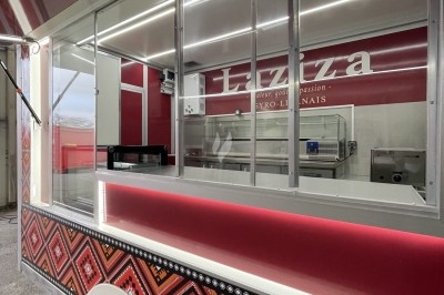 Camion de restauration rouge avec motifs géométriques, équipé d'une vitrine et d'un espace de préparation visible.