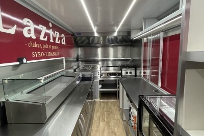 Intérieur d'un food truck moderne avec équipements de cuisine en inox et plancher en bois clair.