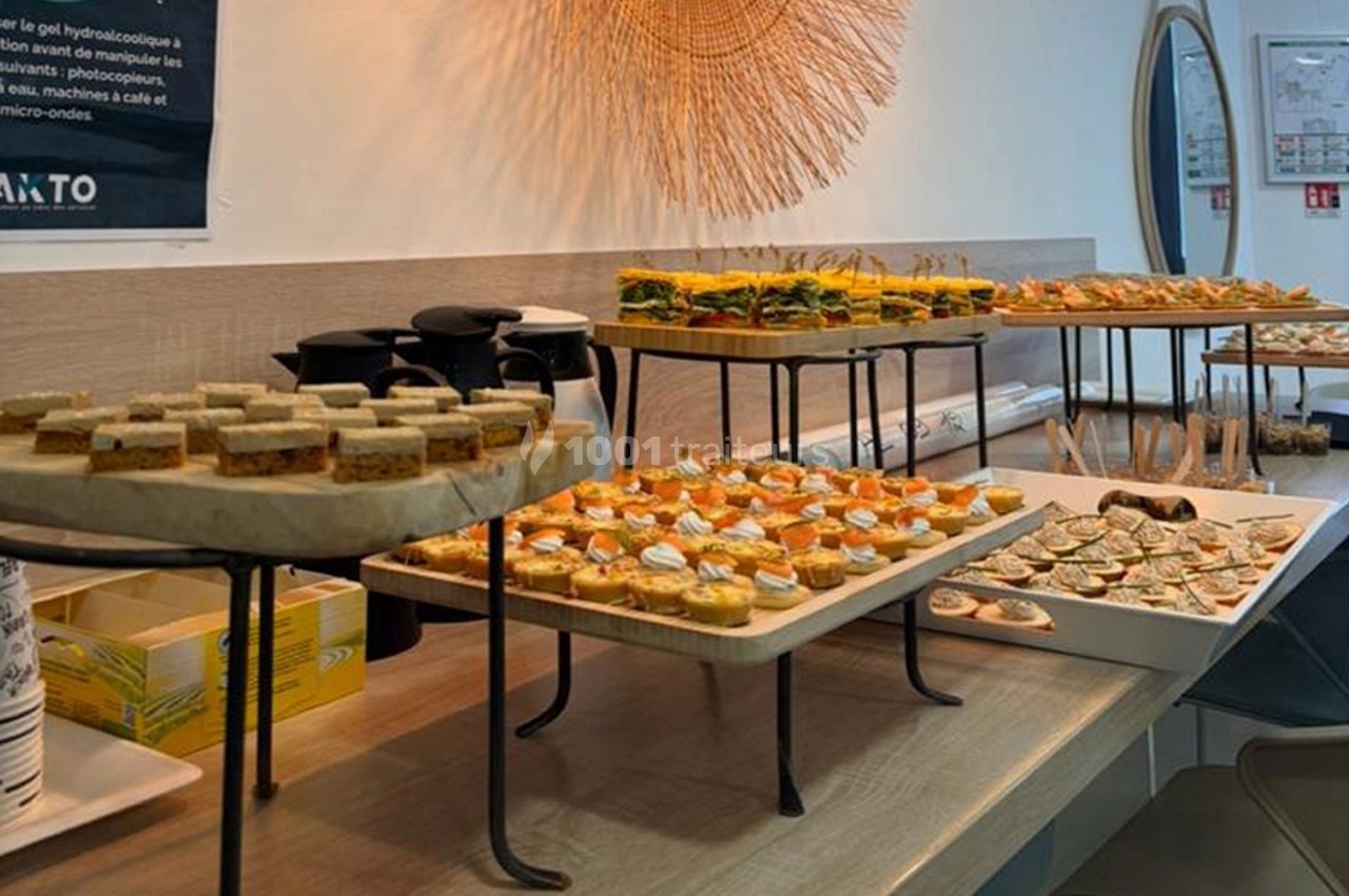 Plateau de petits sandwichs et amuse-bouches variés disposés sur une table dans un espace intérieur lumineux.