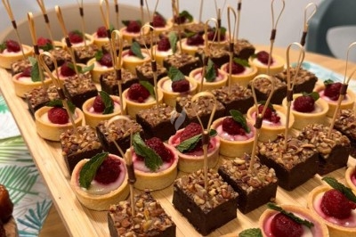 Plateau de mignardises comprenant des tartelettes aux framboises et des carrés de brownie décorés de menthe.