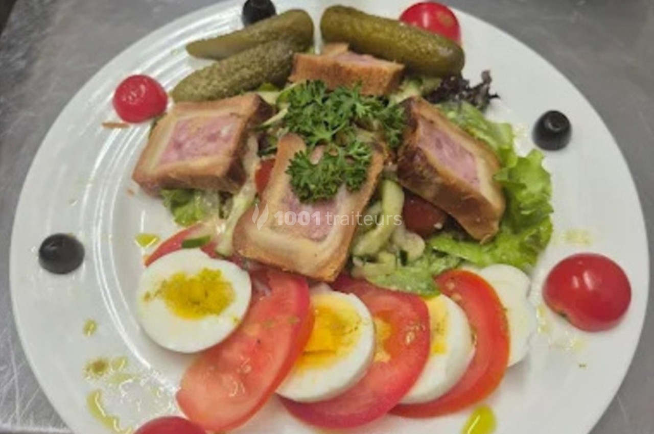 Assiette composée de légumes frais, œufs durs, tomates, cornichons et pâté en croûte, garnie de persil.