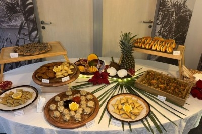 Table garnie de divers plats et desserts exotiques, présentés sur des plateaux en bois avec des décorations tropicales.