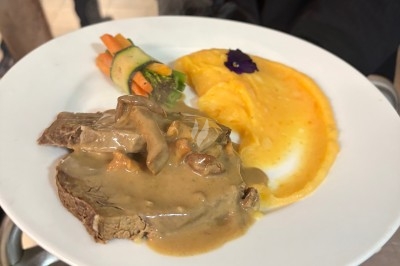 Assiette contenant une tranche de viande sauce aux champignons, purée de pommes de terre et légumes décorés.