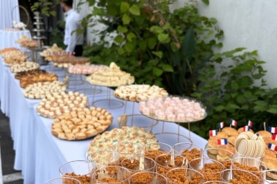 Buffet en extérieur avec une variété de desserts et amuse-bouches disposés sur plusieurs tables alignées.