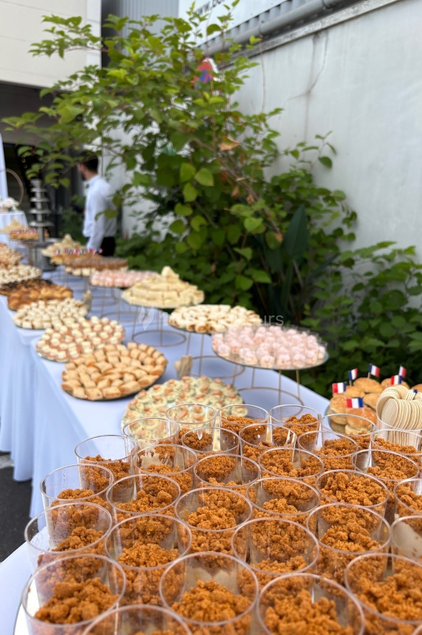 Buffet en extérieur avec une variété de desserts et amuse-bouches disposés sur plusieurs tables alignées.