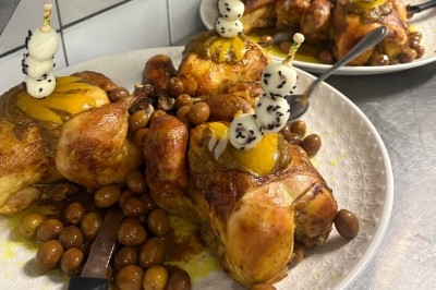 Poulets rôtis garnis de fruits et accompagnés d'olives, présentés sur une assiette blanche.